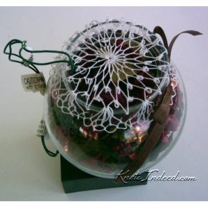 net bowl cover on a bowl with Christmas tree lights and potpourri inside the bowl